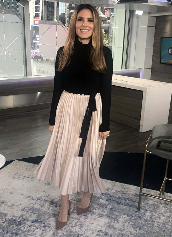 Dina wearing beige pleated skirt with black turtle neck - 2